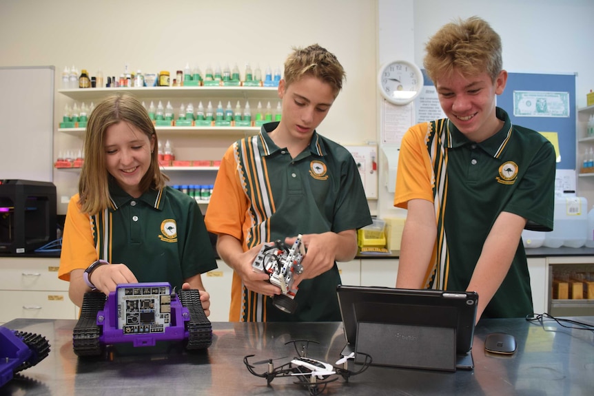 Three students looking down and playing with STEM objects mostly made from LEGO