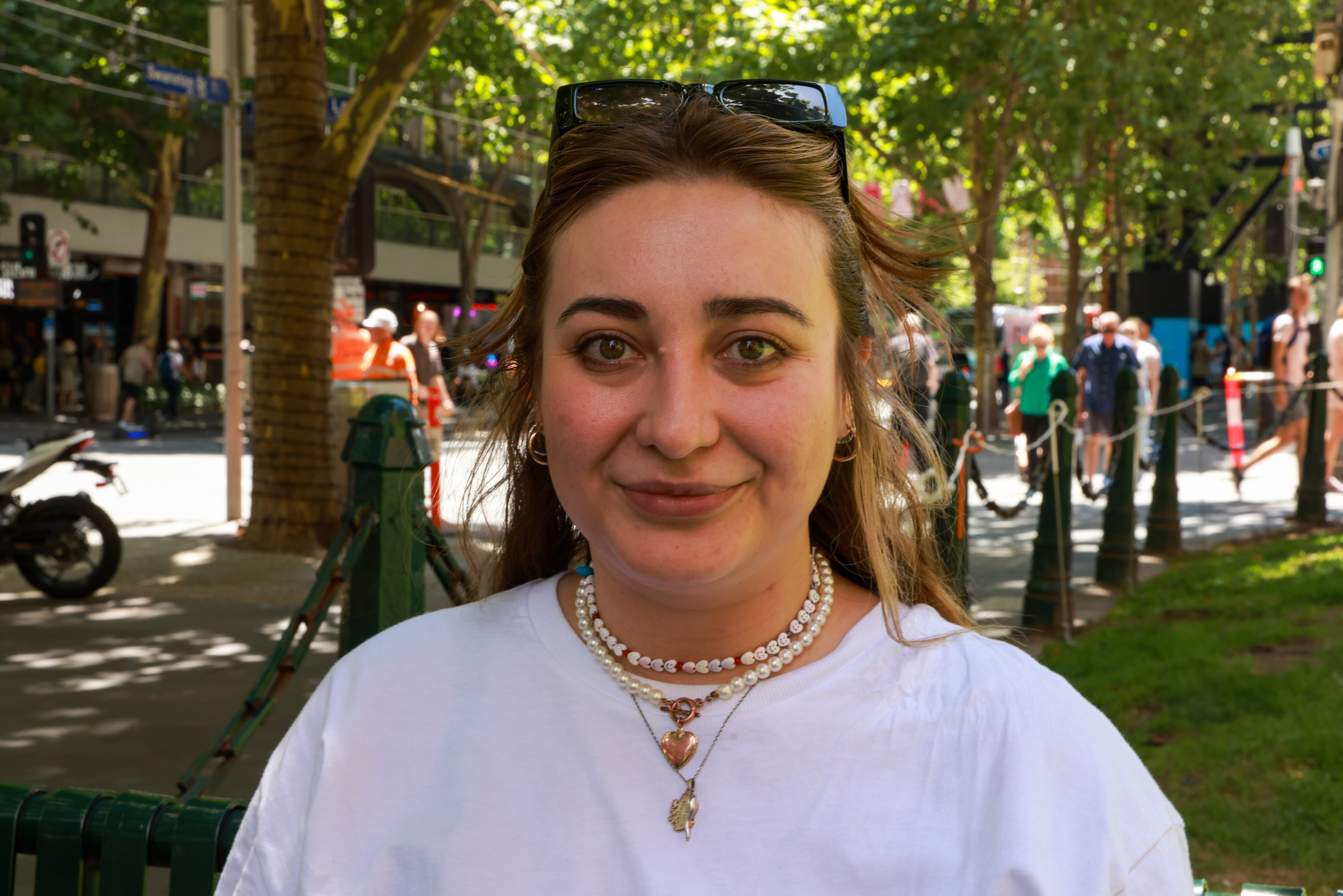 Faded social distance stickers on the footpath and people walking with masks as they pass hand sanitiser stations.
