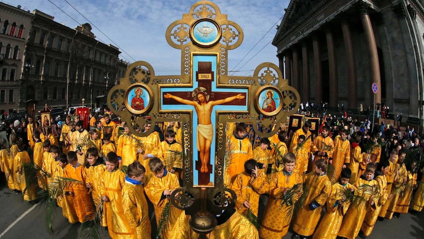 Children in yellow dresses march down a street as part of Palm Sunday celebrations
