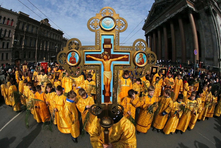 Children in yellow dresses march down a street as part of Palm Sunday celebrations