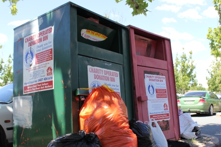 Bags of goods lean against charity bins in a Dickson carpark