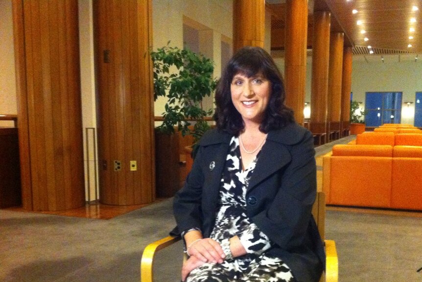 Catherine Ordway sits on a chair and looks at the camera.