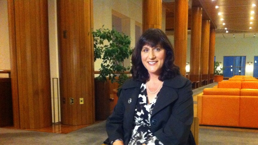 Catherine Ordway sits on a chair and looks at the camera.