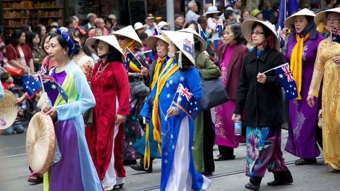 Parade with people wearing cultural dress carrying Australian flags