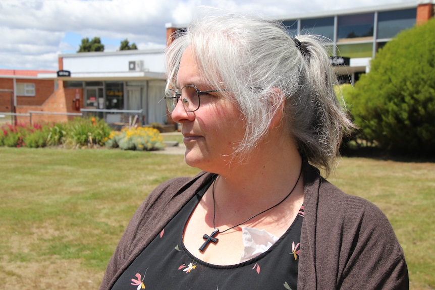 Ellen Evans looks into the distance with a clearly visible Christian pendant.