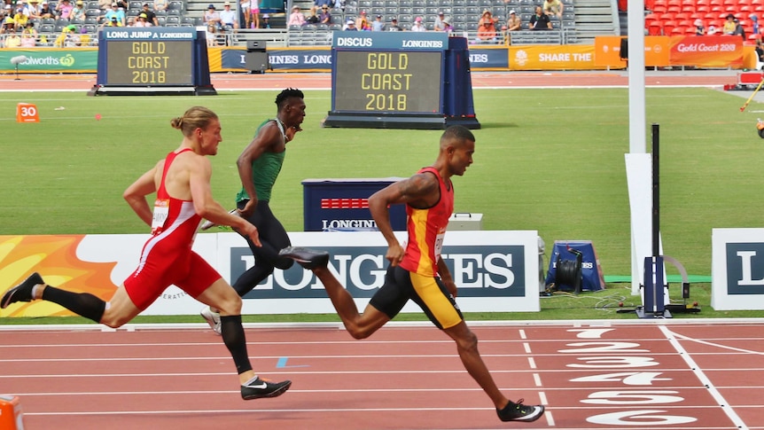 A side on shot of three athletes, including Theo, crossing the finish line.