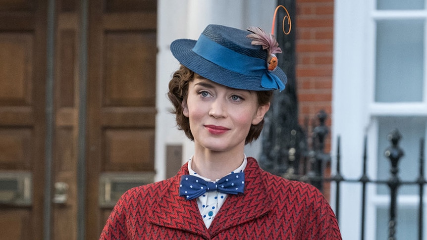 Emily Blunt in costume as Mary Poppins, wearing a red chevron-patterned coat, blue polka-dotted bow tie and shirt, and blue hat.
