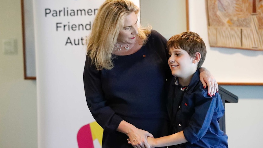 Senator Hughes is hugging her son, who is holding her.