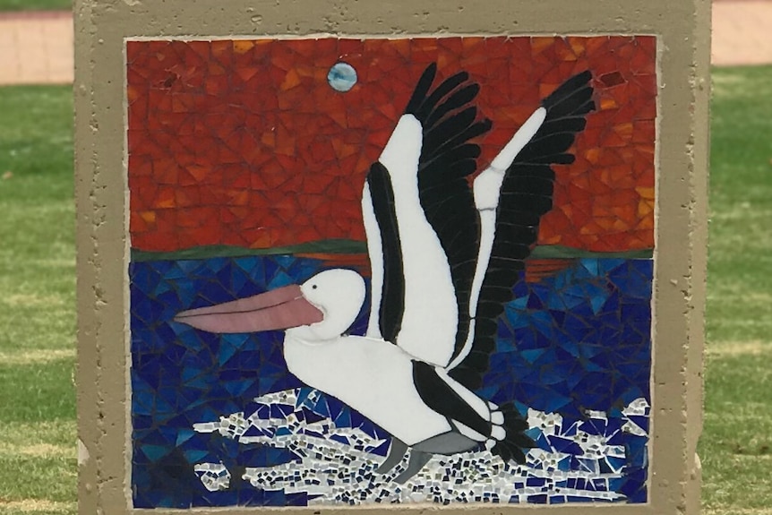 A close up of a painted glass mosaic, a pelican landing on water