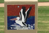 A close up of a painted glass mosaic, a pelican landing on water