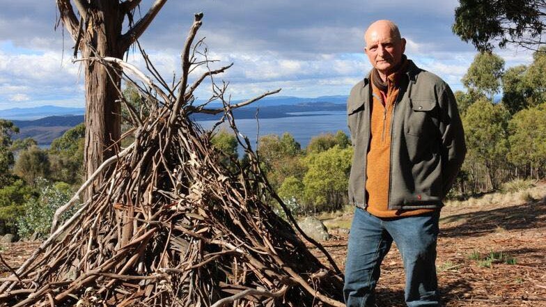 Professor David Bowman standing next to a pile of sticks.