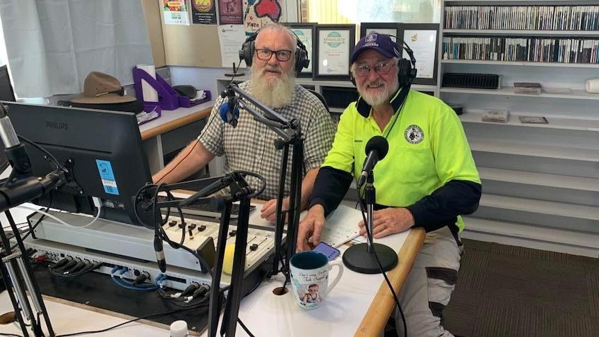 two men smile at camera in radio studio