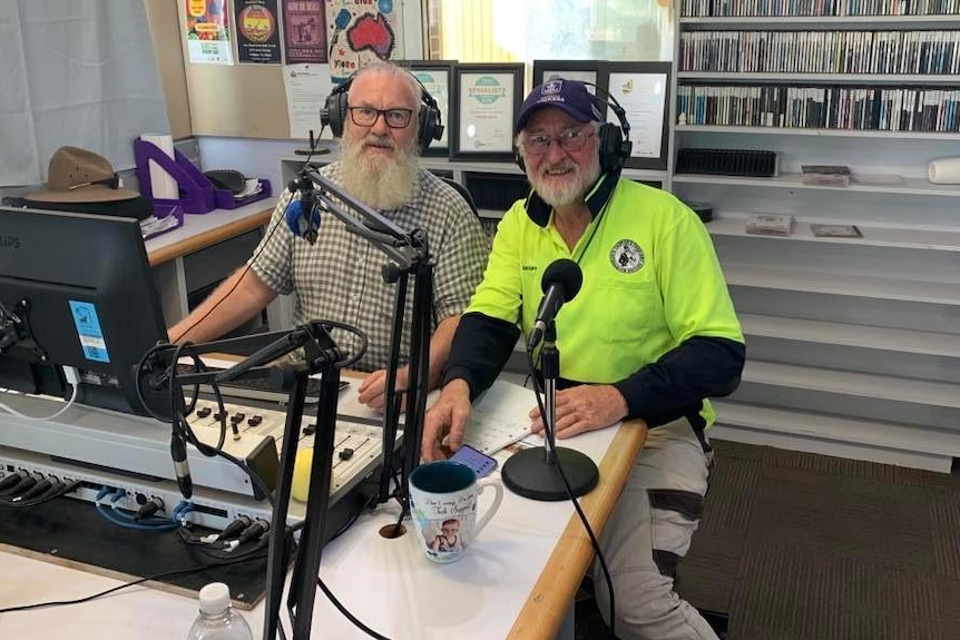 two men smile at camera in radio studio