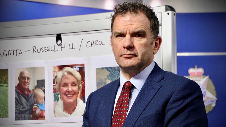 Detective Inspector Andrew Stamper stands in front of a white board with photos of Russell Hill and Carol Clay and maps.