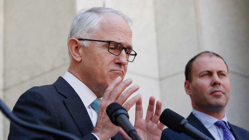 Malcolm Turnbull gestures with both hands, Josh Frdyenberg stands behind him.