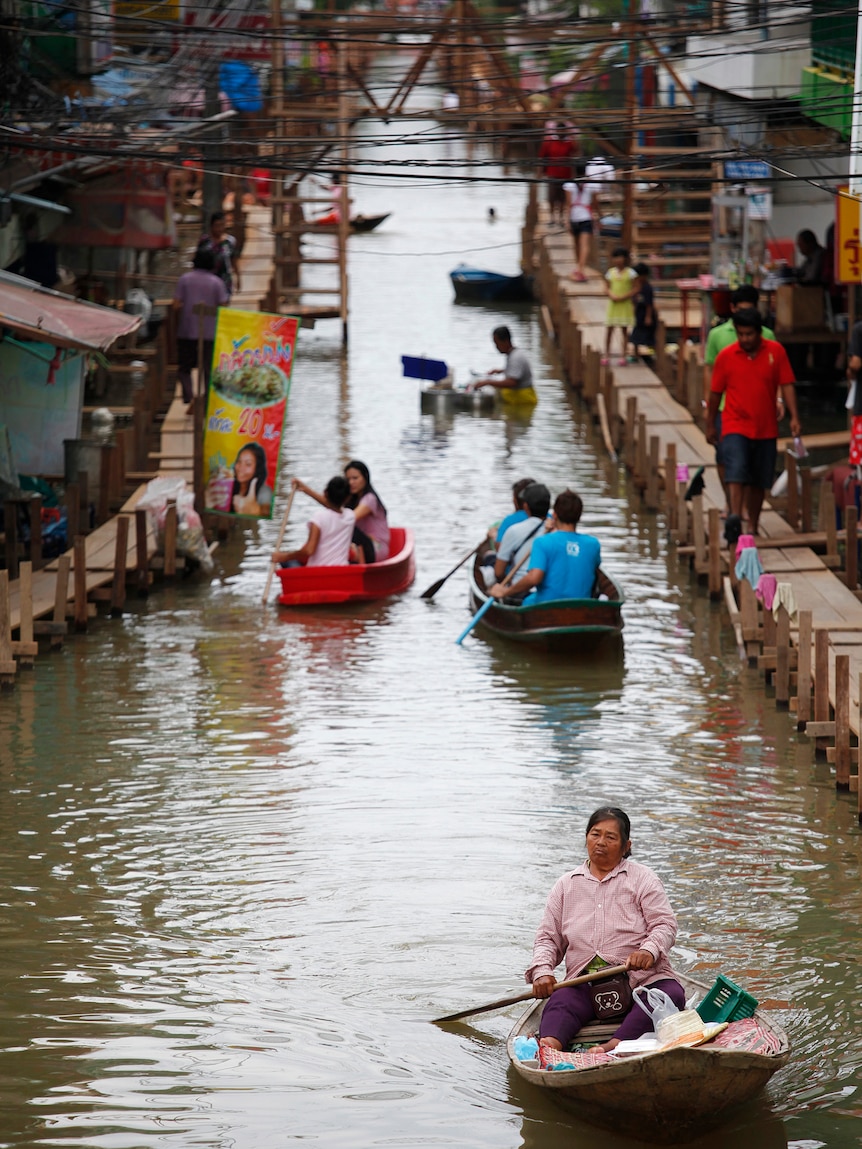 People make their way through a flooded street in the Thai town of Sena