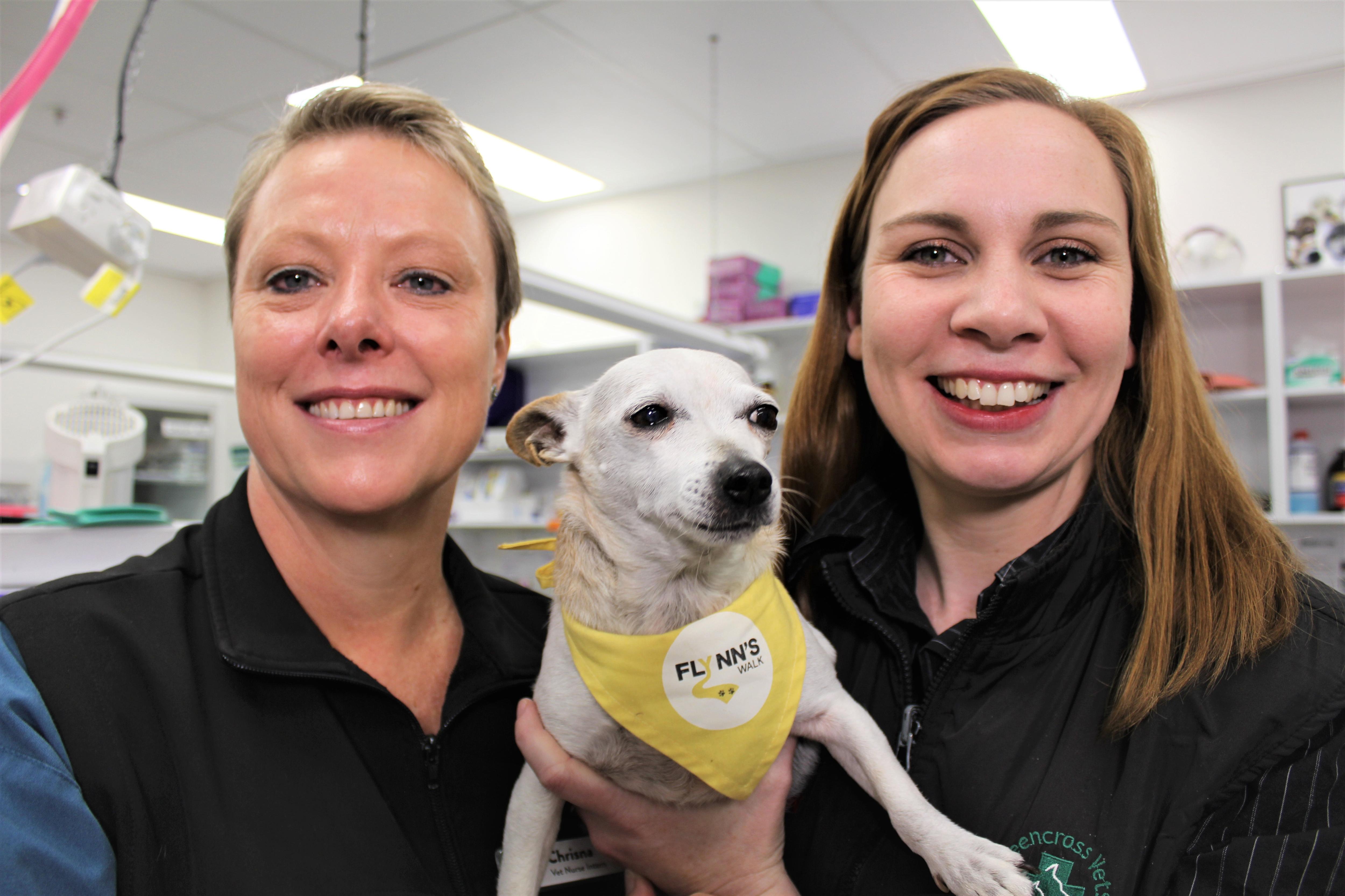 Two women smiling holding a dog