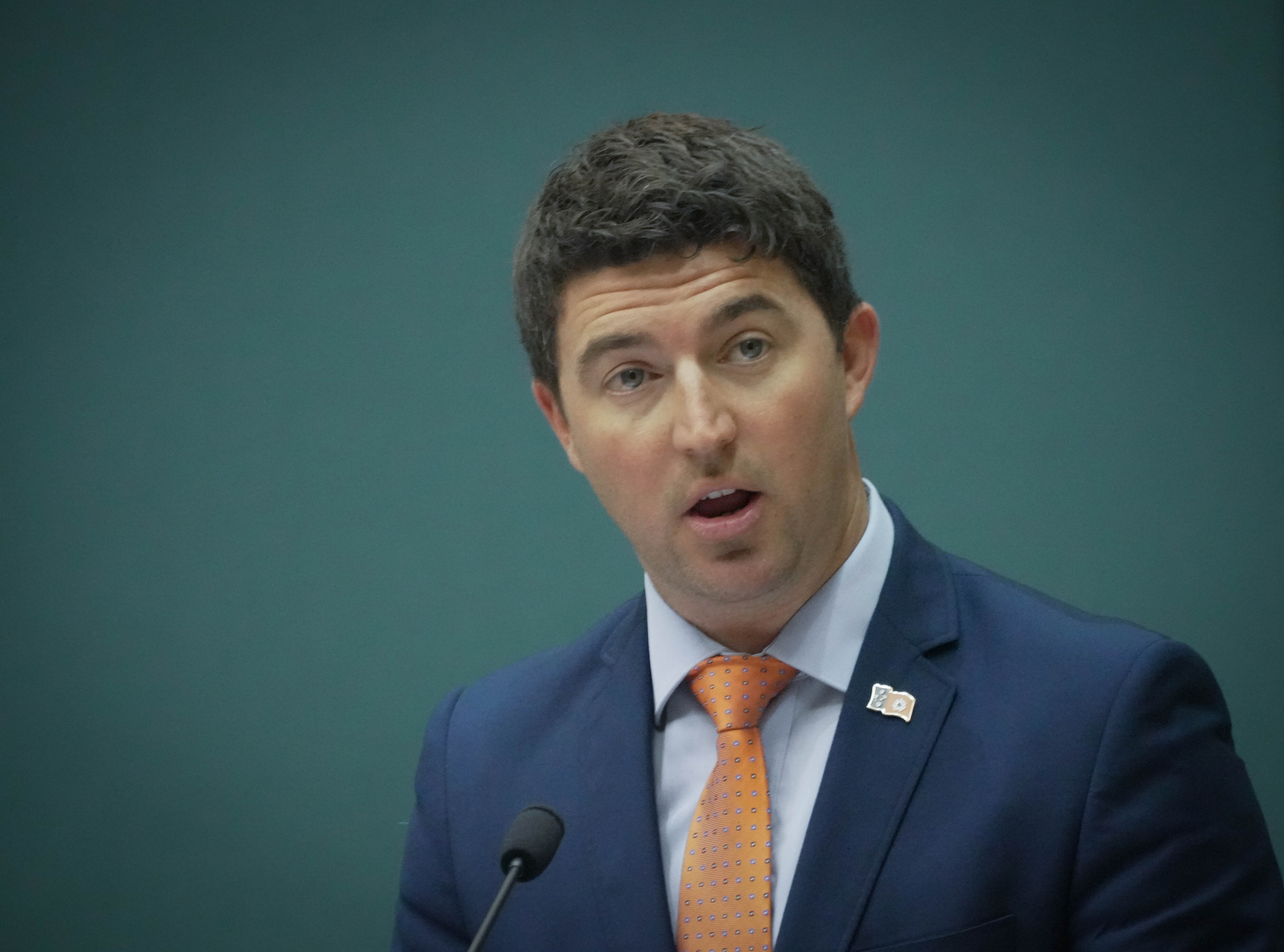 A man wearing a suit and tie, speaking in Parliament.
