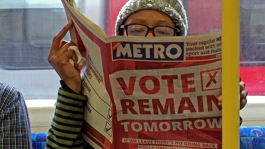 A woman on the London Underground reads a newspaper with a front page saying vote remain tomorrow.