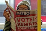 A woman on the London Underground reads a newspaper with a front page saying vote remain tomorrow.