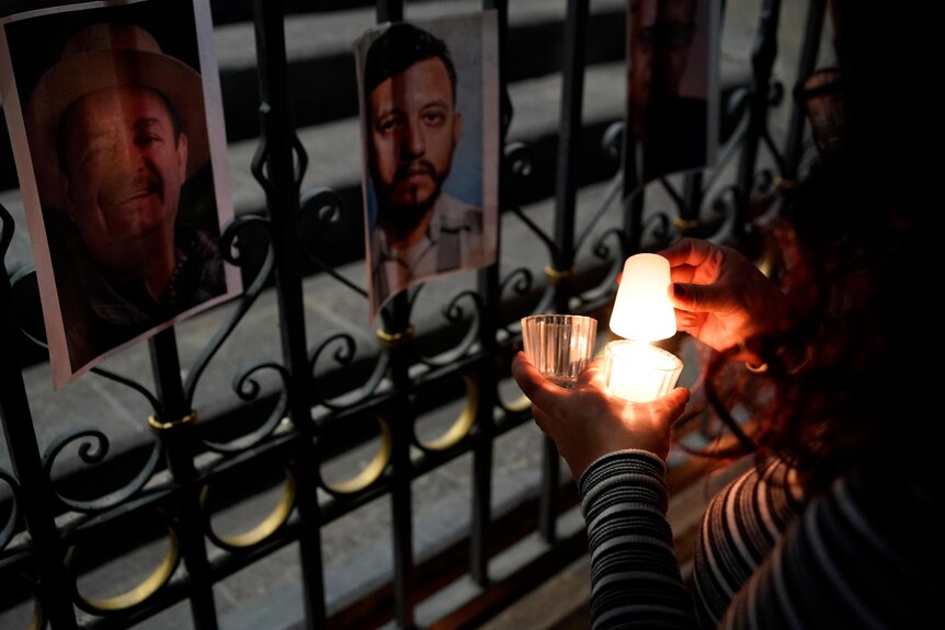 A woman holds a candle next to photos of murdered journalists.