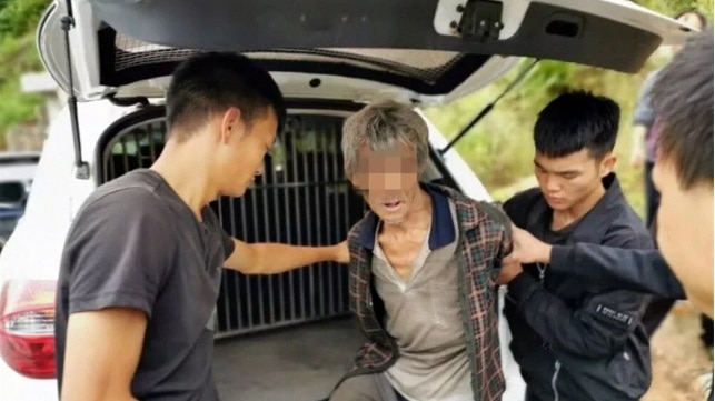 Chinese police carry the emaciated man after apprehending him earlier this month.