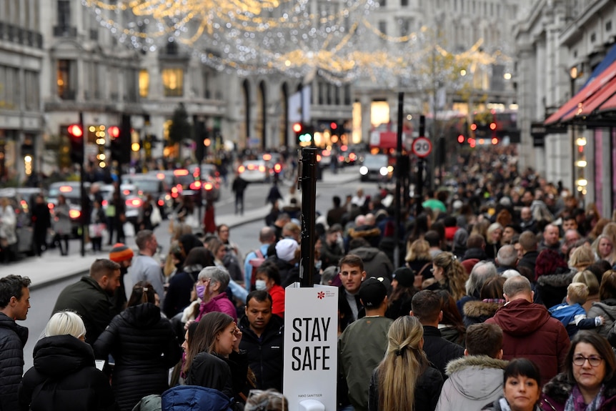 Shoppers walk past a message on a hand sanitiser station in London, November 20, 2021.