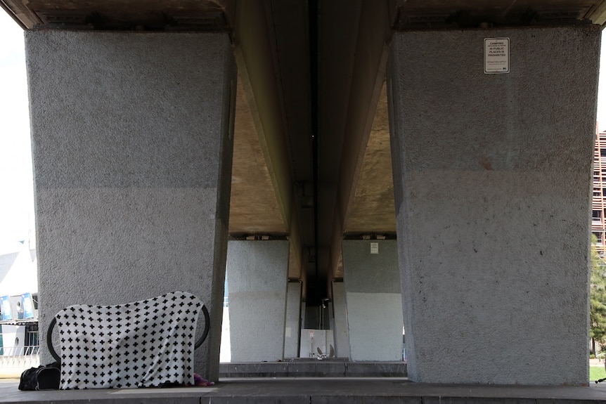 A picture of a bridge under the Flinders Street rail line, with a bike and bags hidden by a sheet.