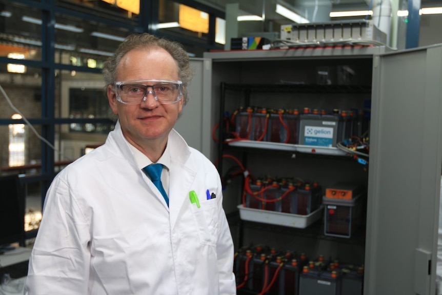 Professor Thomas Maschmeyer stands in front of a row of batteries