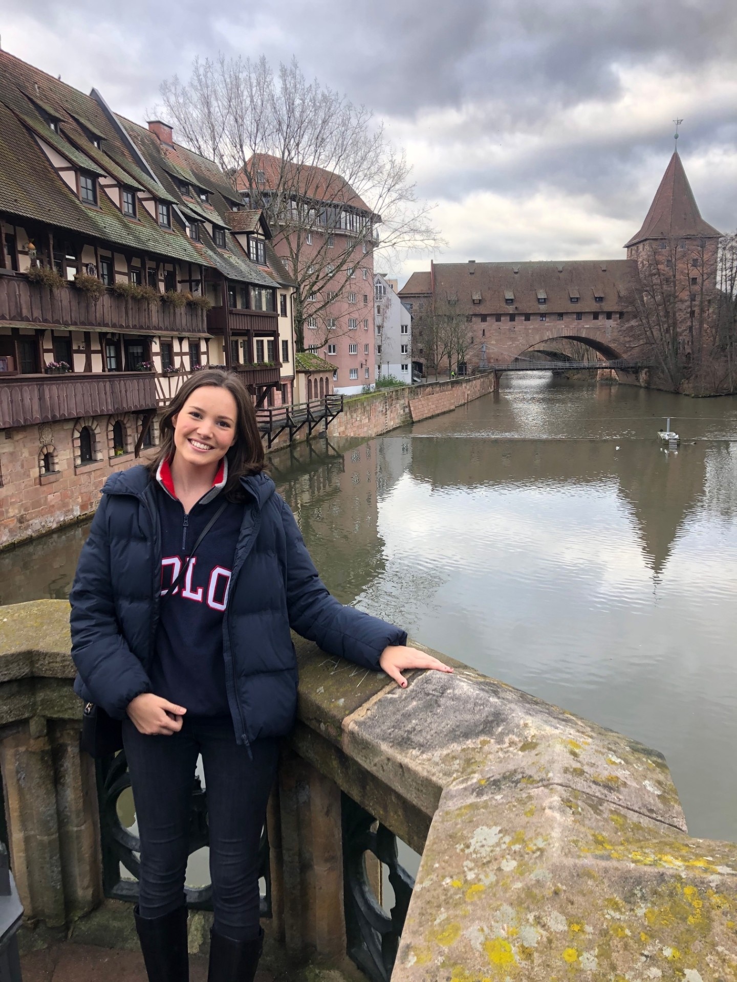 A young woman standing in front of a river and bridge