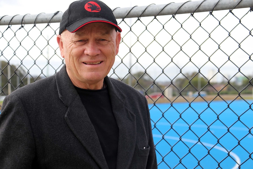 Ric Charlesworth wearing a black cap with a red logo.