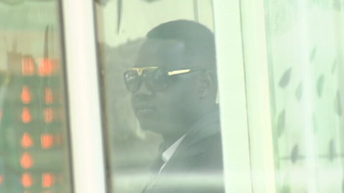 Kuol Deng is seen through a window as he leaves the County Court building in Melbourne.