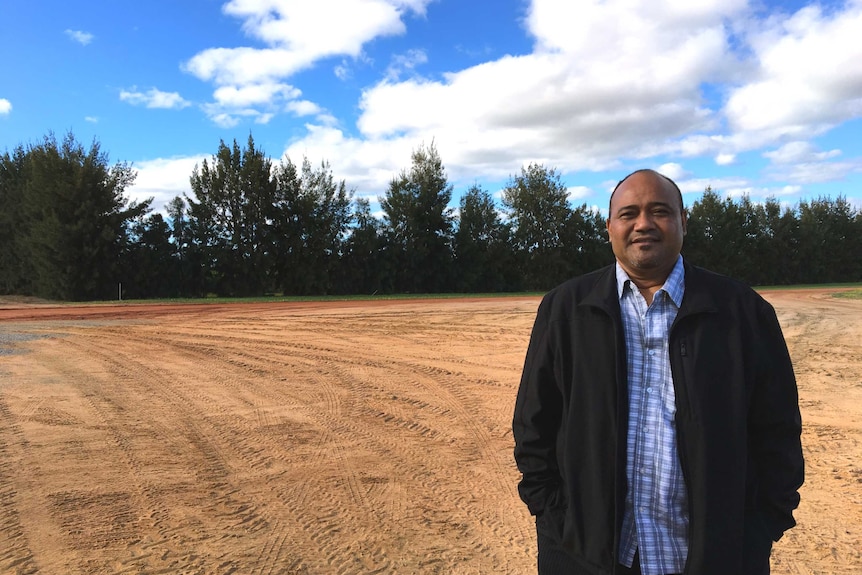 Tongan Minister for Internal Affairs, Hon. Sosefo Fe'ao Vakata, stands in a field next to a citrus orchard