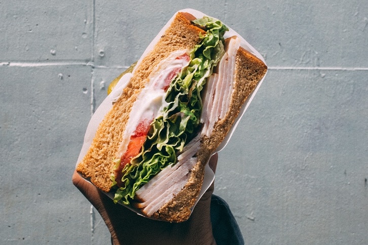 A ham and salad sandwich, held by a student.