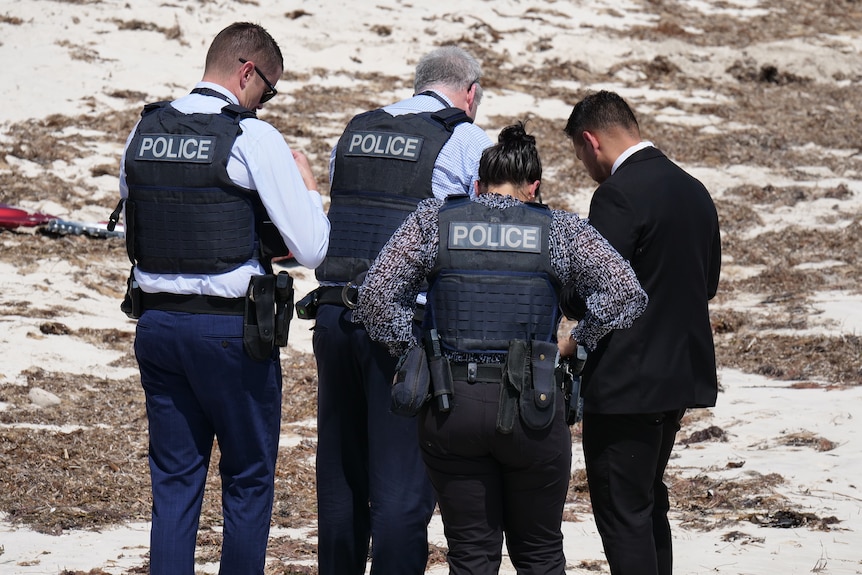 Police gather on a sandy beach