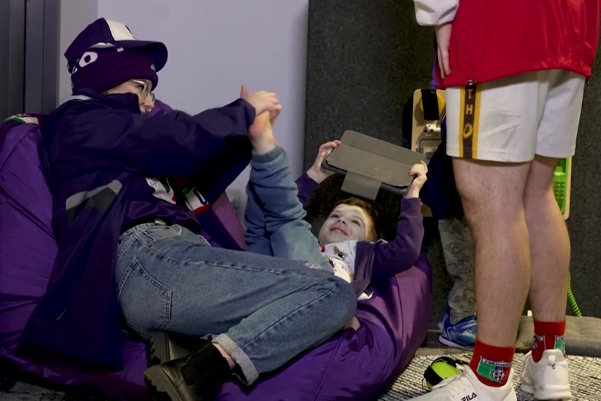 A child and an adult playing with an iPad on a purple beanbag