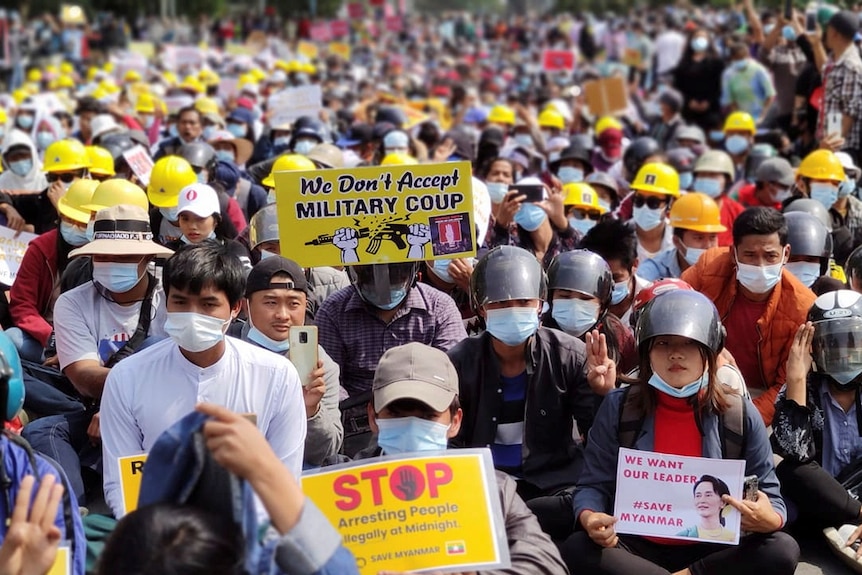 Group of Myanmar citizens wear hats, helmets, mask, hold protest signs