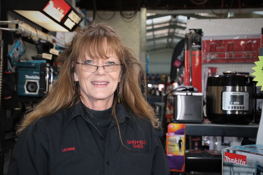 A woman smiles behind a shop counter.