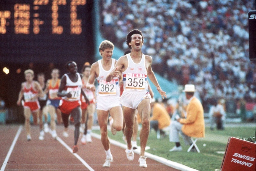 A young Sebastian Coe yells as he runs ahead of others on a running track in front of a large audience.