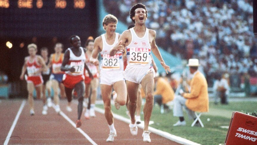 A young Sebastian Coe yells as he runs ahead of others on a running track in front of a large audience.