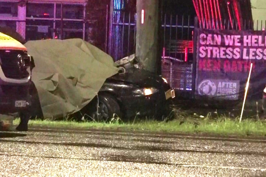 A car crashed into a power pole with a tarp covering the windshield 
