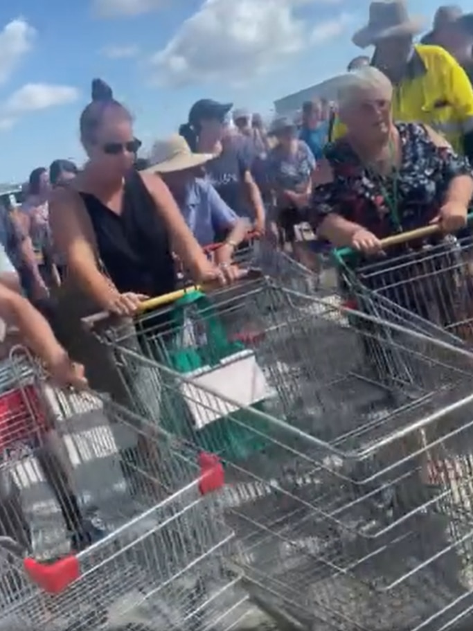People pushing empty trollies through a gate at a tip.