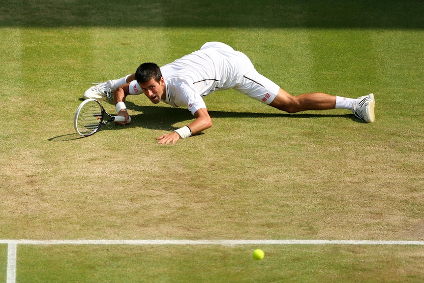 Novak Djokovic almost does the splits after hitting a sliding shot during a match at Wimbledon.