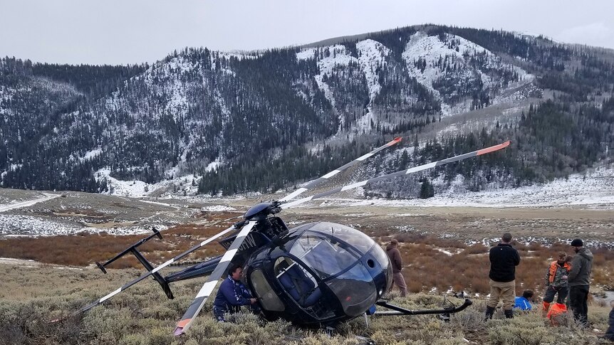 A crashed helicopter sits on a dry, frosty mountainside.