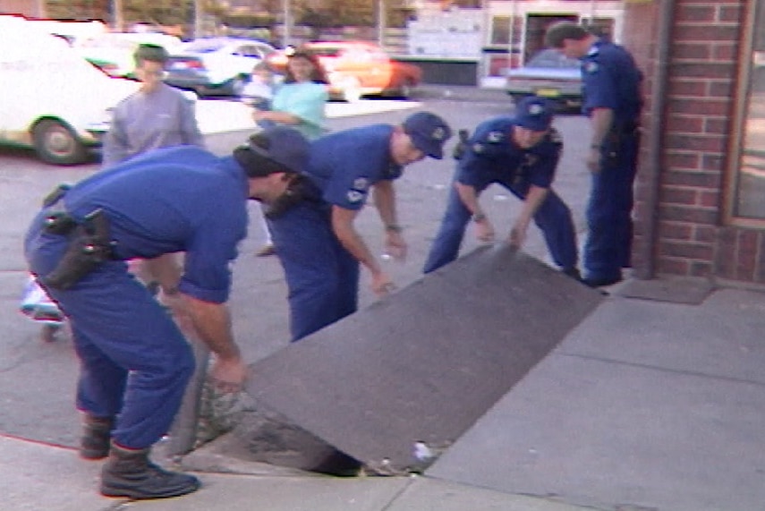 An old TV still of police opening a drain cover