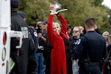 Hollywood celebrity Jane Fonda in handcuffs protesting while wearing a red jacket.