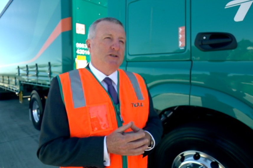 Michael Byrne wears an orange vest and stands in front of a truck