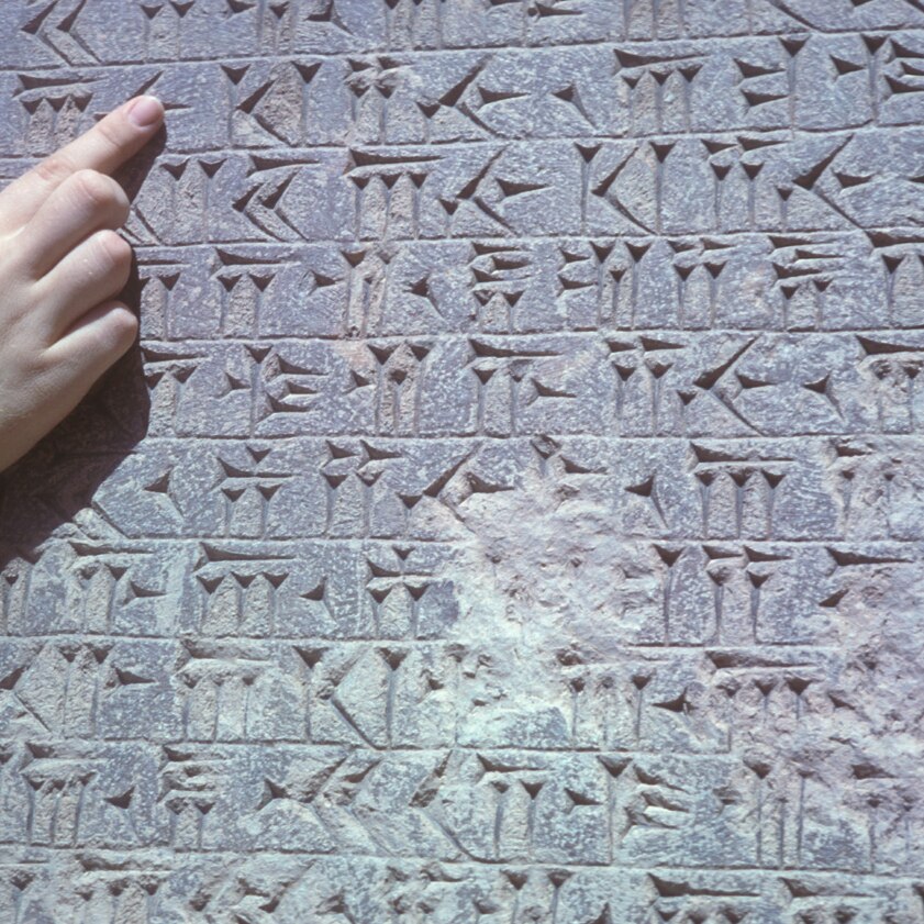 A finger points at some cuneiform inscriptions.