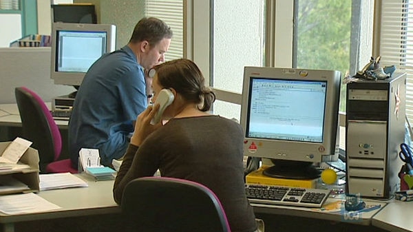 Public servants answer phones and work on computers in an office
