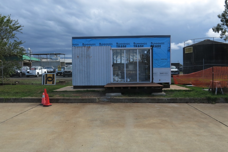 A tiny house, with blue water-proofing and cladding being added over the top. It has sliding doors installed.